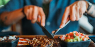 Ein Mann schneidet mit Messer und Gabel ein Stück Fleisch. Es gibt weit weniger Vegetarier als vermutet in Deutschland.