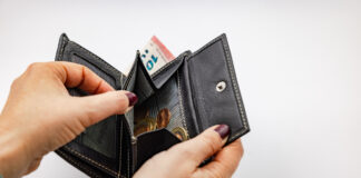 Frau schaut in geöffnetes Portemonnaie mit Kleingeld.
