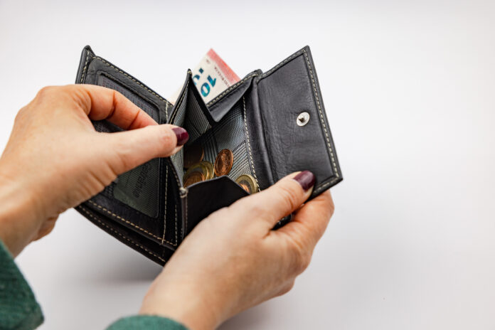 Frau schaut in geöffnetes Portemonnaie mit Kleingeld.