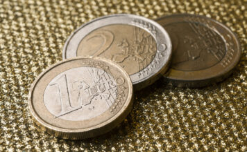 Zwei Ein-Euro-Stücke und ein Zwei-Euro-Stück liegen auf einer Oberfläche.