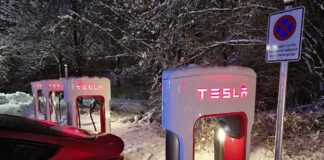 Ein Tesla Elektroauto lädt an einer Tesla Ladesäule im Schnee.