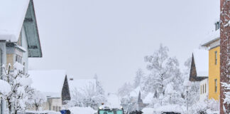 Eine Straße mit Schneeräumfahrzeug und Personen.