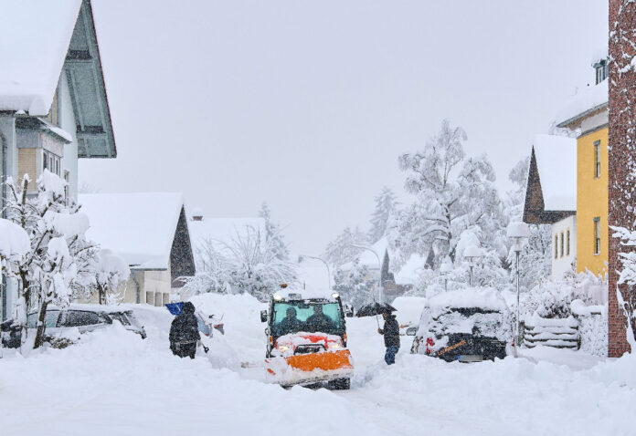 Eine Straße mit Schneeräumfahrzeug und Personen.