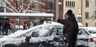 Ein Mann befreit sein Auto von Eis und Schnee.