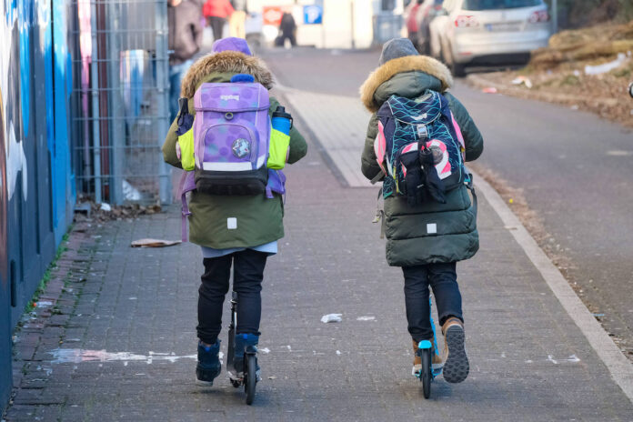 Zwei Kinder mit Roller auf dem Weg zur Kita.