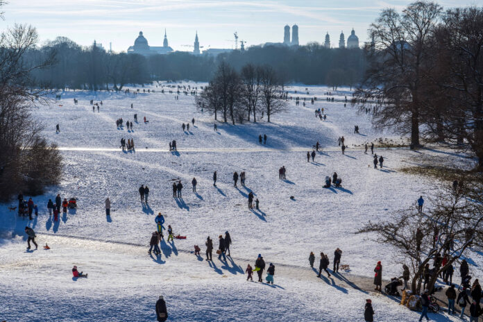 In einem verschneiten Park verbringen viele Menschen den Tag draußen.