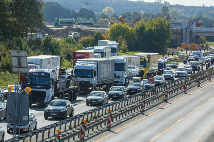 Autos und LKW stehen auf der Autobahn im Stau. Es ist viel Verkehr und die Fahrzeuge stehen auf der Straße eng beieinander.