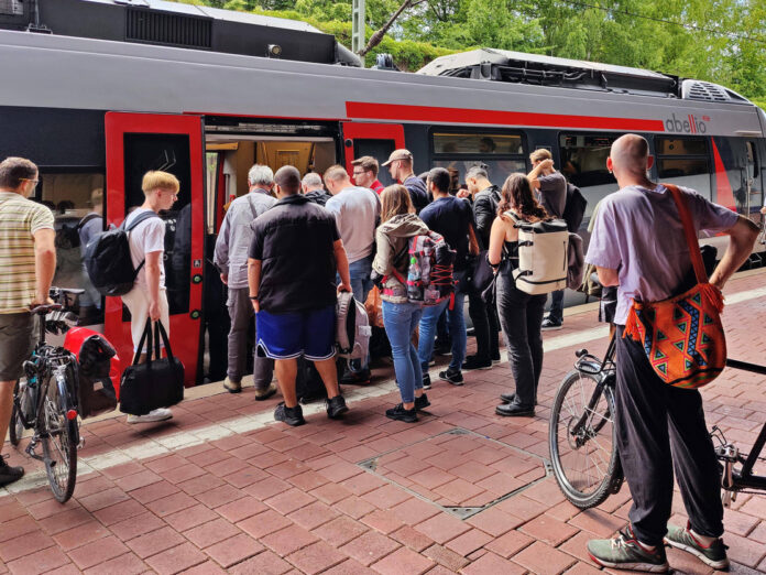 Menschen steigen in einen Zug ein. Das Deutschlandticket soll nun deutlich günstiger werden.