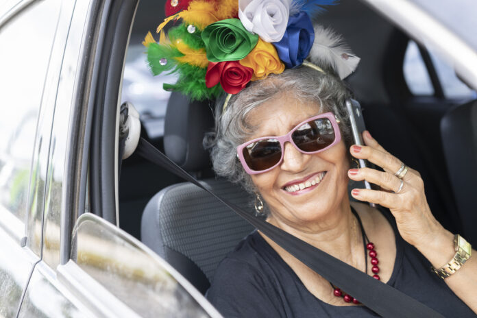ältere verkleidete Frau im auto beim telefonieren