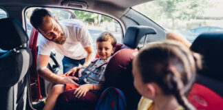 Ein Vater schnallt seine Kinder im Auto an.