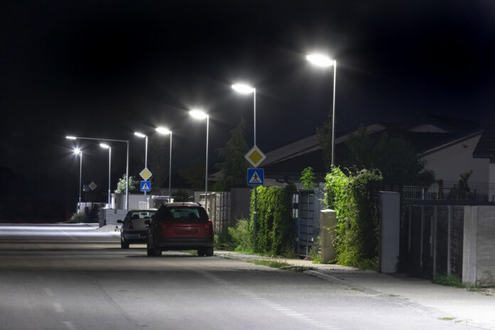 Ein Auto auf einer Straße bei Nacht neben Laternen.