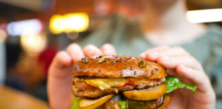 Eine Frau isst in einem Restaurant einen Veggie-Burger.