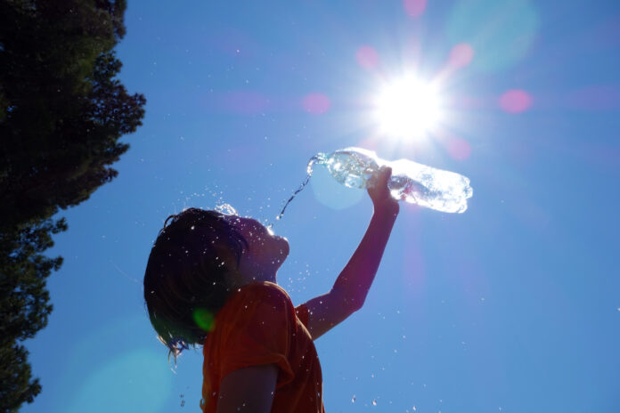 Junge trinkt Wasser in der Sonne. Seit Aufzeichnungsbeginn ist dies der heißeste Januar.
