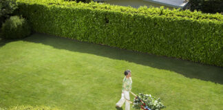 Eine Frau fährt ihre Schubkarre durch den Garten.