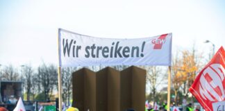 Mehrere Streikende nehmen an einem Protest Teil der Gewerkschaft und zeigen ein Banner mit der Aufschrift: wir streiken. Nun legen Großbetriebe in Karlsruhe ihre Arbeit nieder.