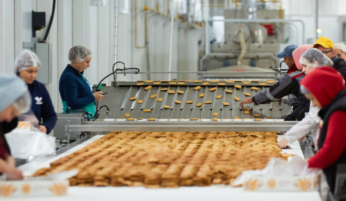 Mehrere Mitarbeiterinnen arbeiten in einer Süßigkeiten-Fabrik an einem Fließband. Ein Traditions-Süßigkeiten-Hersteller ist nun insolvent.
