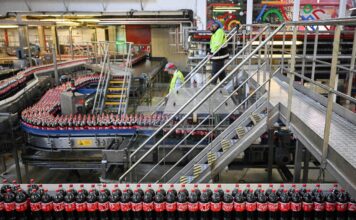 In einer Fabrik werden Coca Cola Flaschen auf einem Laufband transportiert.