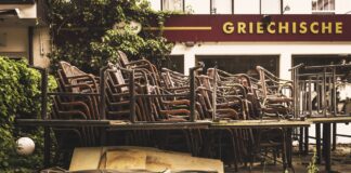 Ein ehemaliges griechisches Restaurant hat geschlossen vor der Tür stehen noch die auch gestapelten Terrassenstühle und Möbel