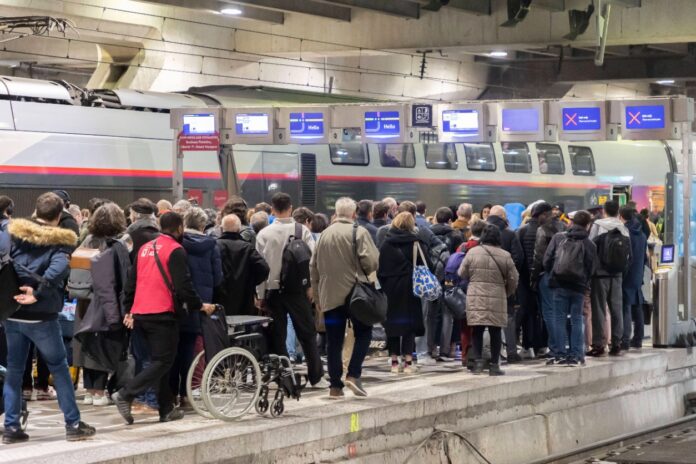 Viele Fahrgäste warten auf das Ankommen der deutschen Bahn oder des ICE am Bahnsteig in einem Bahnhof