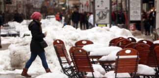 Eine Person in Wintersachen läuft durch eine Innenstadt im Winter mit sehr viel Schnee
