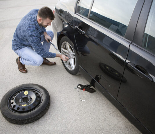 Ein Mann wechselt einen Auto-Reifen.