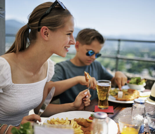 Ein Mädchen und ein Junge essen in einem Restaurant auf einer Terrasse bei schönem Wetter