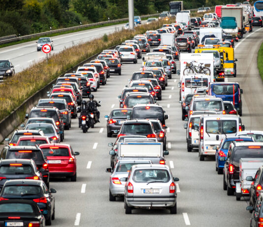 Viele Autos haben ihre Bremslichter an und stehen in drei Reihen auf drei Spuren auf einer Autobahn in Deutschland in einem langen Stau. Das Stauchaos führt zu langen Wartezeiten