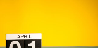 Vor einem gelben Hintergrund zeigt ein Schild den 01. April an.