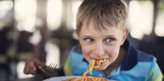 Ein Junge isst Spaghetti im Restaurant.
