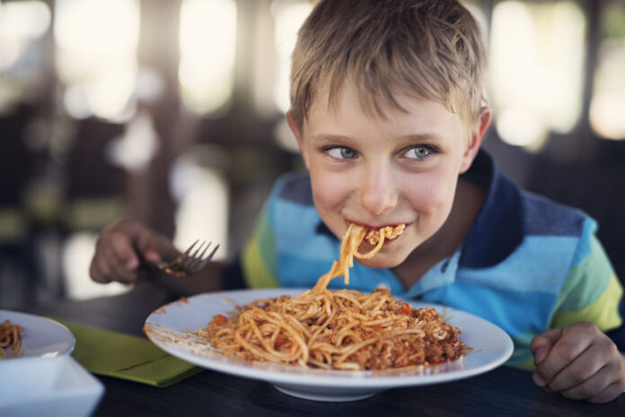 Ein Junge isst Spaghetti im Restaurant.