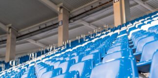 Leere Sitze auf einer Tribüne in einem Stadion.