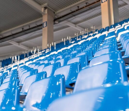 Leere Sitze auf einer Tribüne in einem Stadion.