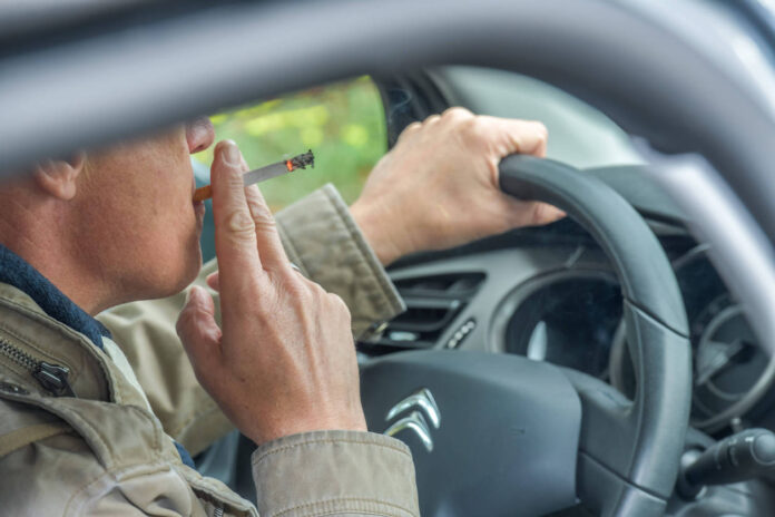 Ein Mann raucht im Auto hinterm Steuer