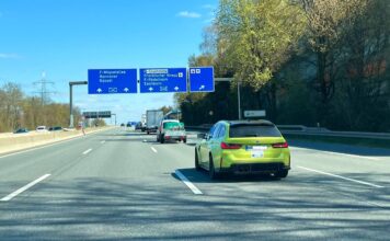 Ein grüner BMW fährt auf einer Autobahn.