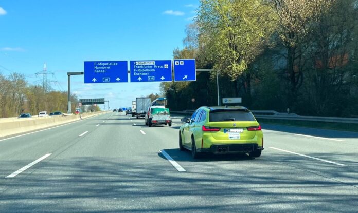 Ein grüner BMW fährt auf einer Autobahn.