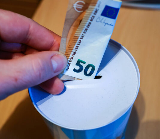 50 Euro werden in eine Spardose gesteckt.