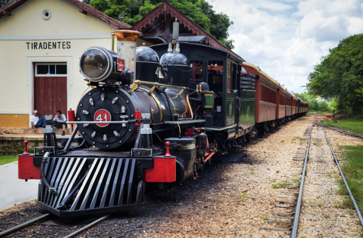 Ein nostalgischer Zug fährt quer durch Karlsruhe auf den Schienen. Mit dabei sind die Fahrgäste. Der schwarze Zug ist reich verziert.