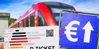 Eine Hand hält ein Deutschlandticket. Daneben befindet sich ein blaues Schild mit einem weißen Euro-Zeichen und einem weißen Pfeil darauf. Im Hintergrund fährt ein Zug.