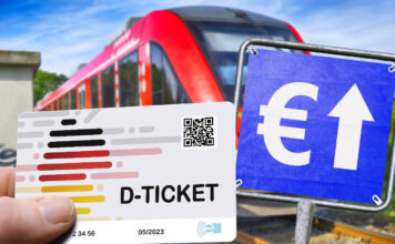 Eine Hand hält ein Deutschlandticket. Daneben befindet sich ein blaues Schild mit einem weißen Euro-Zeichen und einem weißen Pfeil darauf. Im Hintergrund fährt ein Zug.