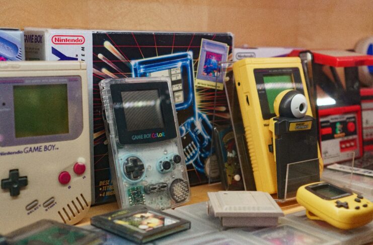 Es stehen viele, alte Spielkonsolen nebeneinander. Davor liegen die passenden Spiele dazu.