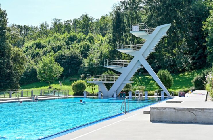 Ein großes Schwimmbad und ein Schwimmbecken mit einer Wasserrutsche und einem Springturm im Sommer
