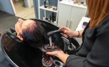 Eine Friseurin wäscht die Haare ihrer Kundin im Waschbecken.