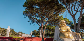 Ein Feng-Shui-Park mit einer goldenen Buddha-Statue im Vordergrund und auf einer Mauer positionierten Statuen anderer buddhistischer Gottheiten lädt den Besucher zum Entspannen und Verweilen ein.