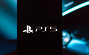 Schwarze PlayStation 5 Gaming Konsole von Sony mit großem Logo. Im Hintergrund verschwommener wireless PS Controller und LED Gaming-Beleuchtung in blau.