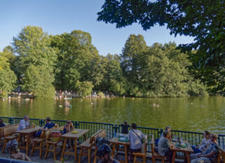 Eine Fischerhütte an einem See, die Essen und Getränke anbietet, sodass Touristen gemütlich an Tischen sitzen können und Essen und Getränke bei dem Blick auf den See genießen können