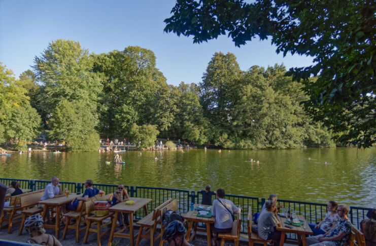 Eine Fischerhütte an einem See, die Essen und Getränke anbietet, sodass Touristen gemütlich an Tischen sitzen können und Essen und Getränke bei dem Blick auf den See genießen können