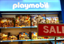 Verschiedene Playmobil Spielwaren-Packungen stehen in einem Regal. Davor steht ein Schild mit der Aufschrift "Sale". Die Playmobil-Figuren mit Zubehör scheinen im Angebot zu sein.