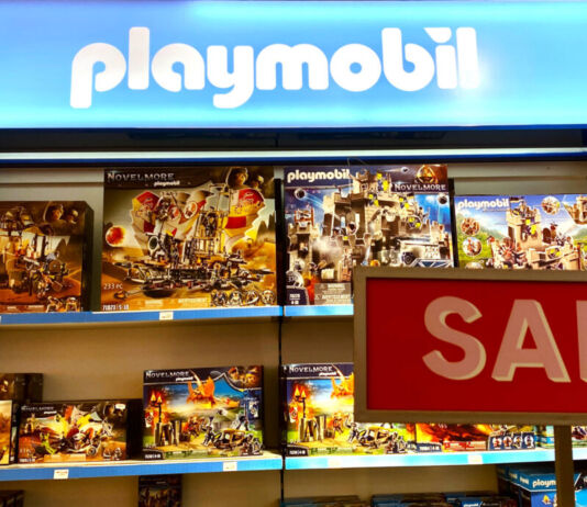 Verschiedene Playmobil Spielwaren-Packungen stehen in einem Regal. Davor steht ein Schild mit der Aufschrift "Sale". Die Playmobil-Figuren mit Zubehör scheinen im Angebot zu sein.