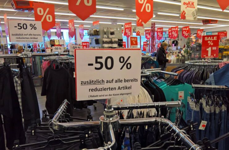 Ein Schild mit der Aufschrift "50 Prozent auf bereits reduzierte Ware" kündigt den Schlussverkauf in einem Geschäft oder Discounter an.