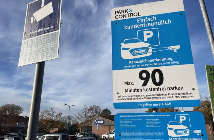 Ein Schild weist auf die Kennzeichenerkennung beim Parken auf einem Parkplatz hin. Für 90 Minuten können die Bürger kostenfrei parken.